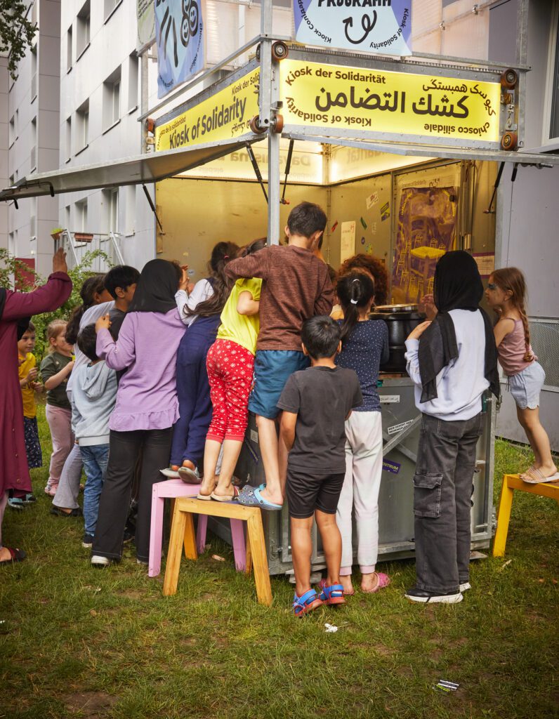 Kinder dr&auml;ngen sich um den mobilen Kiosk, um einen Blick hinein zu bekommen.
