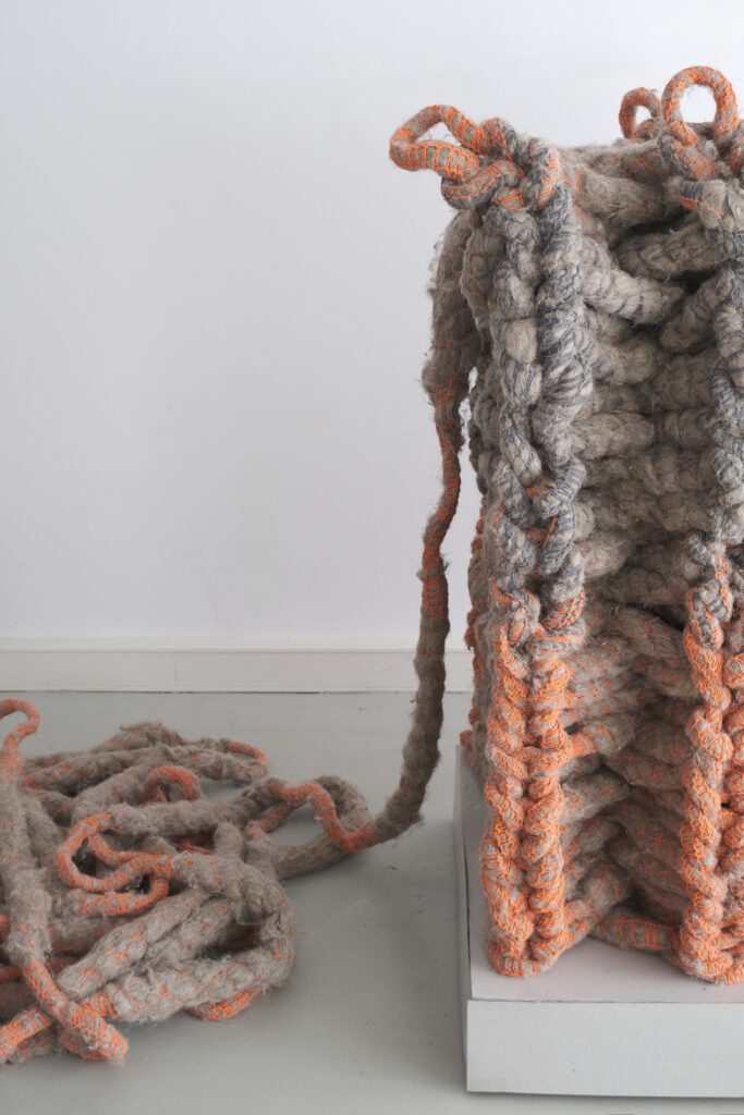 A flexible, net-like installation made of intertwined yarns as part of the "Architectural Yarns" project in a room. The textile structure consists of interconnected fibers.