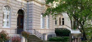 Außenansicht des Hauses der Kultur in Bonn mit historischer Fassade, Eingangstreppe und einem Schild im Vordergrund mit der Aufschrift “HAUS DER KULTUR / Kulturpolitische Gesellschaft e.V.”.