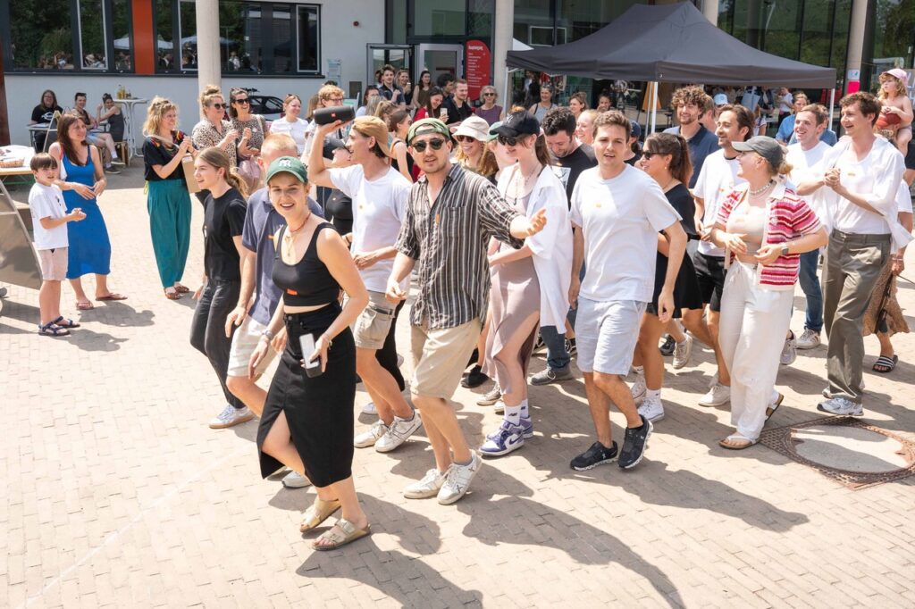 Menschen tanzen während einer Veranstaltung auf dem Campus der Alanus Hochschule; im Hintergrund sind Zelte, Tische und Stände aufgebaut.