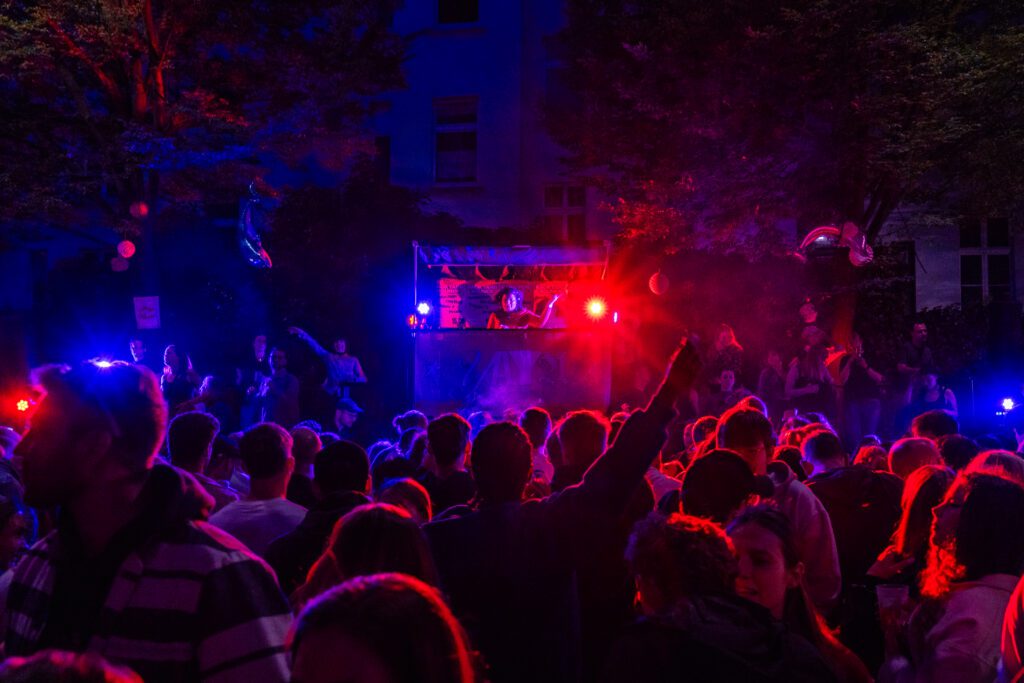Open-Air-B&uuml;hne mit DJ-Pult und Publikum bei einer Veranstaltung des Netzwerks YAYA.