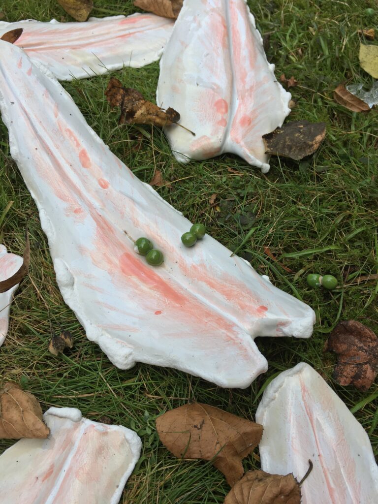 Detailaufnahme der Installation &bdquo;Pangasius&ldquo; mit Keramikobjekten in Form von Fischfilets und einzelnen Erbsen auf dem Boden.