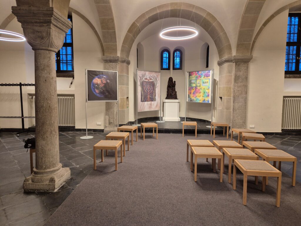A church interior with seating and three display panels on topics related to climate and faith (in front of a sculpture).