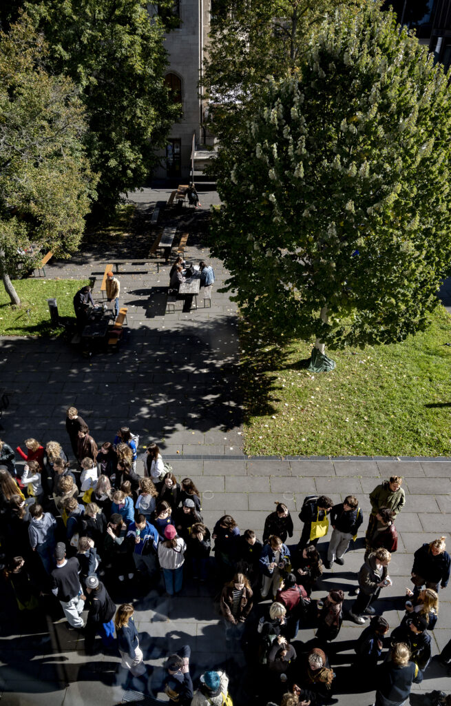 Menschenansammlung auf dem Gelände der Burg Giebichenstein. Einige Menschen unterhalten sich miteinander, ein paar sitzen auf Bänken und lernen.